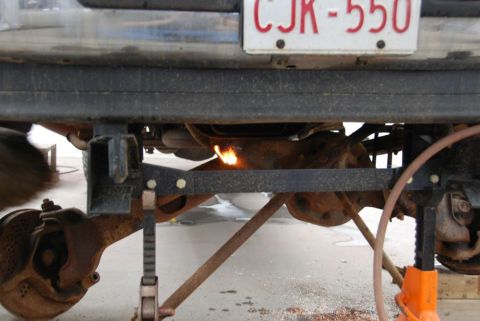 1996 Ford Bronco - Working on the undercarriage of a vehicle with a torch, license plate CJR-550 is visible.