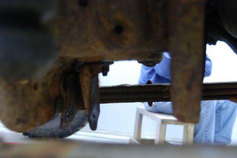 1996 Ford Bronco - A close-up shot reveals the heavily rusted undercarriage of a vehicle, focusing on the leaf springs and suspension system.