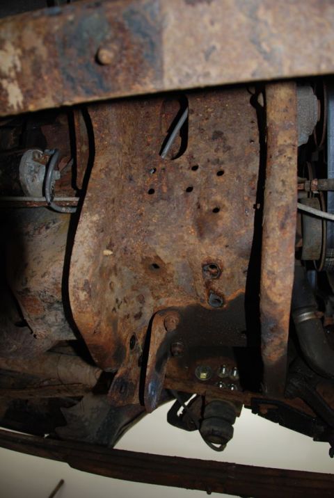 1996 Ford Bronco - Close-up view of heavily rusted vehicle frame and suspension parts, showing significant wear and tear.