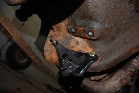 1996 Ford Bronco - Close-up of a black bracket bolted to the rusty frame of a vehicle's undercarriage.