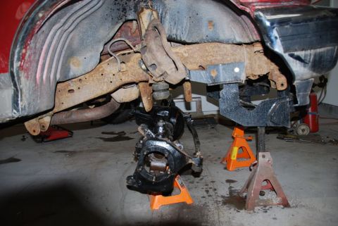 1996 Ford Bronco - The vehicle's front suspension and frame are disassembled and supported by jack stands in a garage.