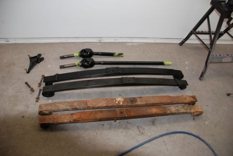 1996 Ford Bronco - Leaf springs and suspension parts laid out on a garage floor.