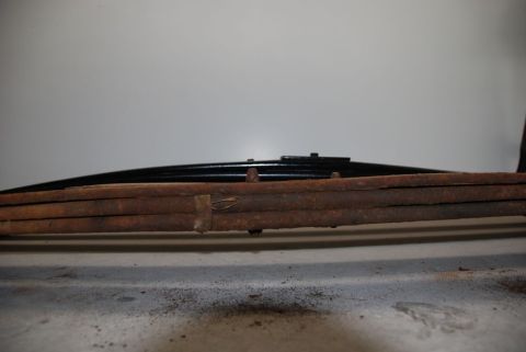 1996 Ford Bronco - A close-up view of a rusty leaf spring, a component of a vehicle's suspension system.