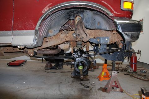1996 Ford Bronco - The suspension and chassis of a red 1996 Ford Bronco are visible as it undergoes repair work.
