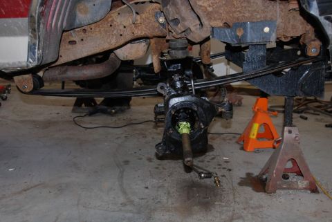 1996 Ford Bronco - Close-up of vehicle suspension and frame components being worked on, with parts supported by jack stands.