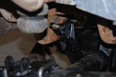 1996 Ford Bronco - Close-up view of a vehicle's undercarriage components, including rusty pipes and a black bracket.