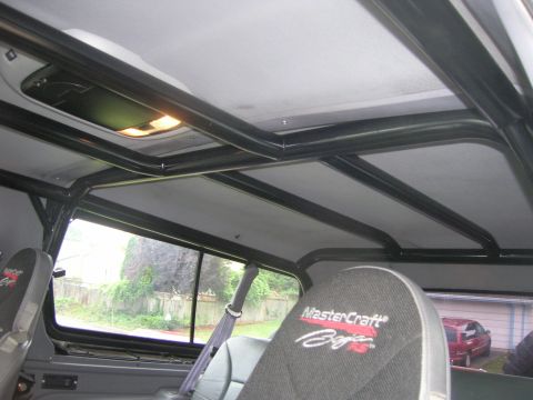 1996 Ford Bronco - The interior of the vehicle features a roll cage and custom seats, with a red SUV visible outside.