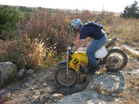 1993 Suzuki RMX250 - Rider maneuvers a dirt bike through a challenging, rocky off-road course.