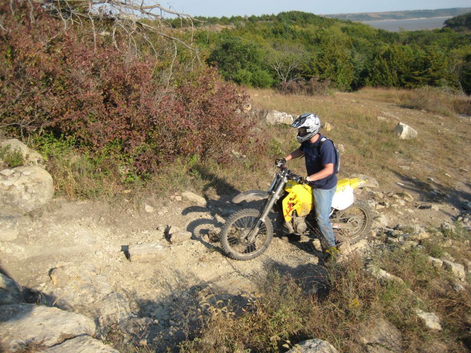 Yellow dirt bike on rocky trail with rider