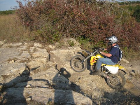 1993 Suzuki RMX250 - Rider on a yellow dirt bike maneuvers through a challenging rocky terrain on an outdoor trail.