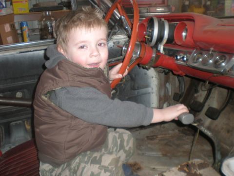 1963 Ford Galaxie - A young boy sits behind the wheel of a vintage car, ready for a restoration project.