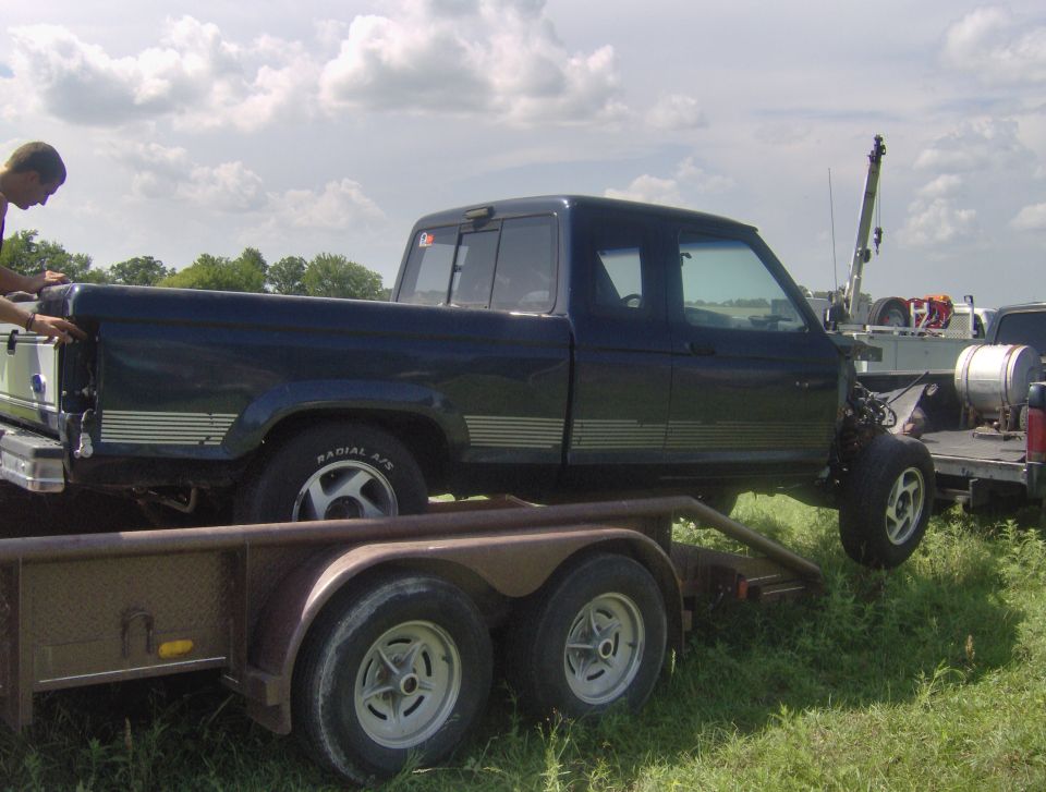 Side view of dark blue pickup truck being loaded onto a trailer