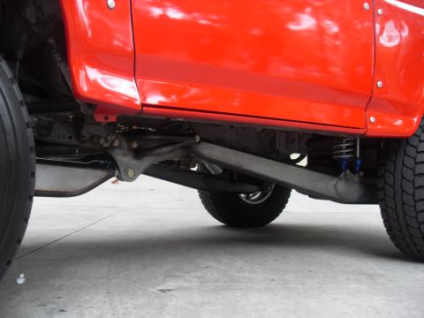 1990 Ford Bronco - Close-up view of the undercarriage and suspension system of a red SUV.