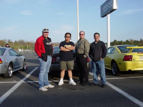 2001 Ford Mustang - A group of men pose for a photo in a parking lot, with two Ford Mustangs visible in the background.