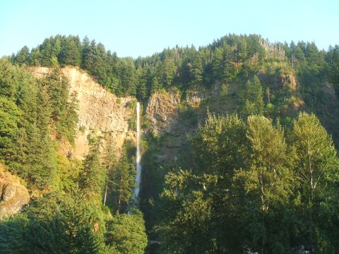 1974 Ford Ranchero - A scenic view of a tall waterfall flowing down a cliff, framed by dense evergreen trees and a bright sky.