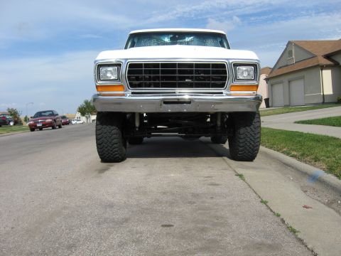 1979 Ford Bronco - Front view of a white 1979 Ford Bronco, lifted with prominent off-road tires.