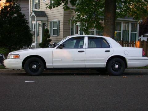 2000 Ford Crown Victoria - A white 2000 Ford Crown Victoria sedan is seen from the side, parked on a residential street.