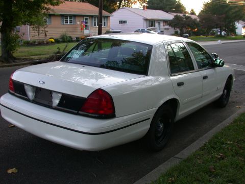 2000 Ford Crown Victoria - This white 2000 Ford Crown Victoria is parked on a residential street with houses in the background.