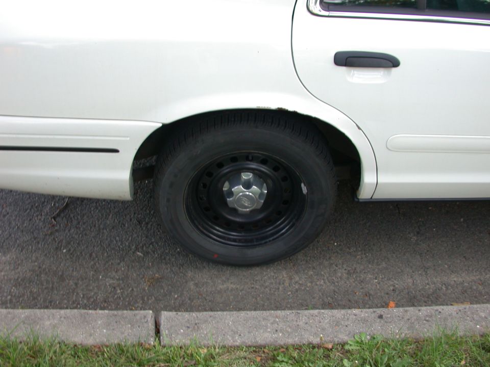 White sedan's rear wheel and door handle, side view