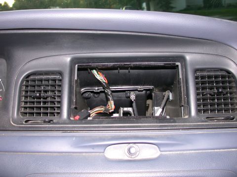 2000 Ford Crown Victoria - The dashboard of a 2000 Ford Crown Victoria shows an empty radio slot with visible wiring and air vents.