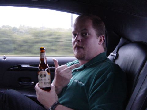 2001 Ford Mustang - A man holds a beer bottle while sitting in the passenger seat of a car, with the landscape blurred in the background.