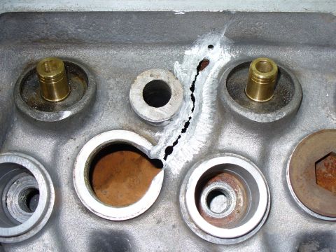 1971 Toyota Corolla - Close-up of a cracked engine cylinder head showing a repair attempt with visible brass valve guides.