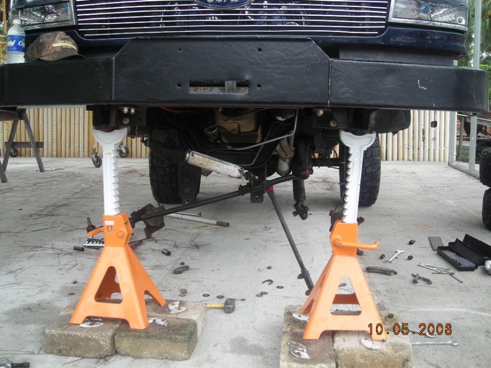 Front suspension of SUV on jack stands, with tools scattered nearby