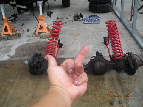 1993 Ford Bronco - Front axle assembly with red coil springs, likely from an off-road vehicle, undergoing maintenance.
