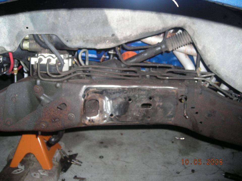 close-up of vehicle frame and brake lines, supported by an orange jack stand