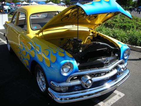 1998 Ford Crown Victoria - A classic car with a custom paint job and open hood is displayed at an outdoor event.