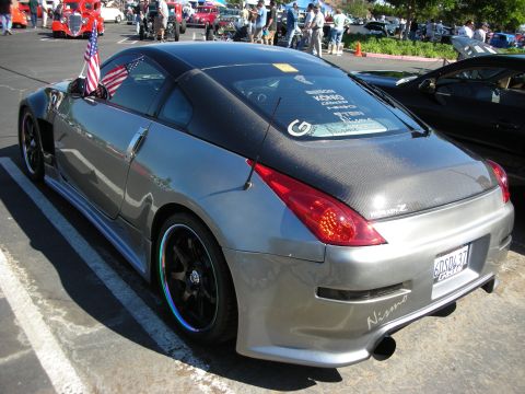 1998 Ford Crown Victoria - A silver Nissan 350Z is parked at a car show, with other vehicles and people in the background.