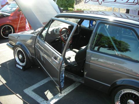1998 Ford Crown Victoria - A modified gray hatchback is displayed with its doors open, parked next to another vehicle.