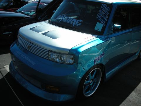 1998 Ford Crown Victoria - A customized blue and silver vehicle with prominent racing decals and hood scoops is parked at a car show.