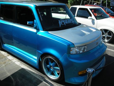 1998 Ford Crown Victoria - Customized blue Scion xB at a car show, parked next to a white pickup truck.