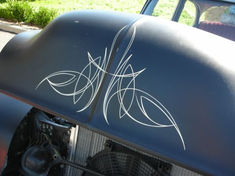 1998 Ford Crown Victoria - A close-up view of a car's hood intricate white pinstriping and exposed engine parts below.