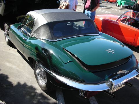 1998 Ford Crown Victoria - A green Jaguar E-Type convertible is parked at a car show, with other vehicles visible in the background.