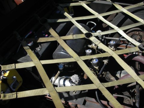 1998 Ford Crown Victoria - Close-up view of engine components, including an air compressor and various gauges, held in place by a cargo net.