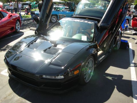 1998 Ford Crown Victoria - A black sports car with its doors open, parked at an outdoor event with other vehicles present.