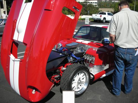 1998 Ford Crown Victoria - A red sports car with white racing stripes is displayed with its hood open, revealing the engine compartment.