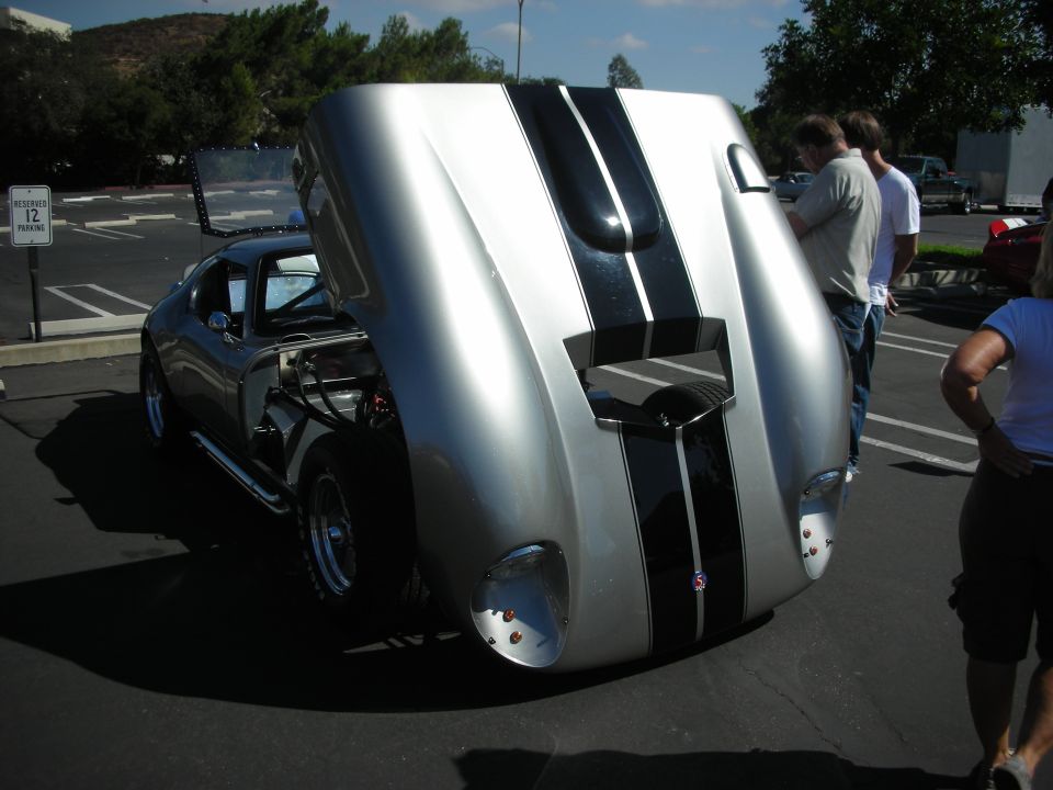 Silver sports car with black stripes, hood open revealing engine