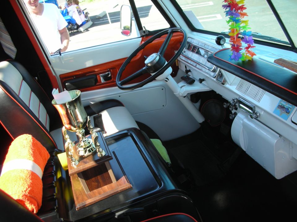 Van interior with trophy on center console, orange towel, and colorful lei decoration