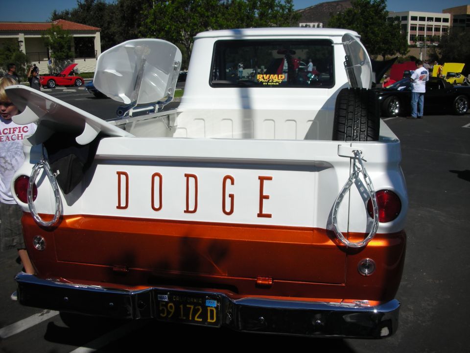 Rear view of white and orange Dodge pickup truck with surfboard and spare tire