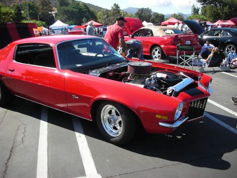 1998 Ford Crown Victoria - Red 1970s muscle car on display at a car show, engine exposed for viewing.