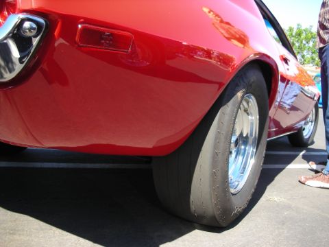 1998 Ford Crown Victoria - The rear wheel and fender of a bright red classic car are shown in this close-up shot.