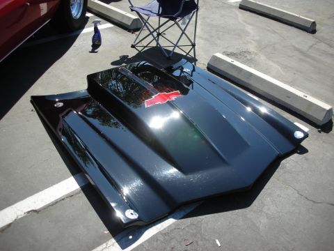 1998 Ford Crown Victoria - A black hood with a red Chevrolet bowtie emblem sits on the ground at an outdoor event.