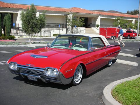 1998 Ford Crown Victoria - A bright red 1962 Ford Thunderbird convertible with a white roof is parked at an outdoor event.