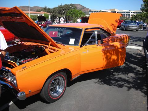 1998 Ford Crown Victoria - An orange muscle car is displayed with its hood and door open at an outdoor car show.
