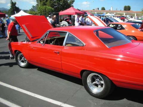 1998 Ford Crown Victoria - A red coupe is parked at an outdoor car show with its hood open, revealing the engine compartment.