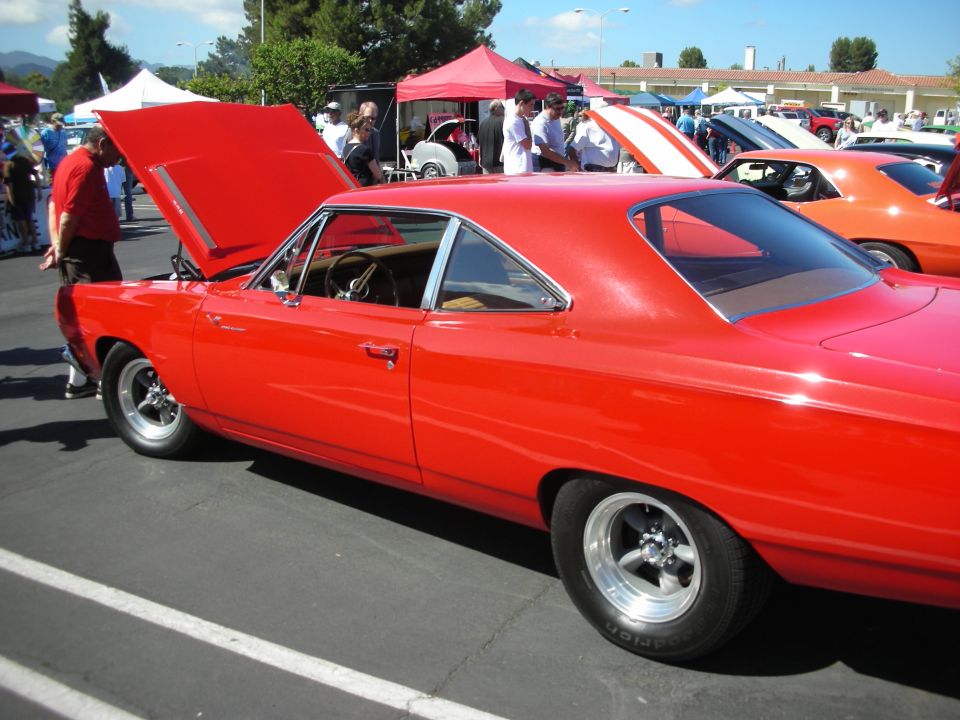 Red coupe with hood open, showing interior and engine bay. Chrome trim, aftermarket wheels, and drag tires are visible