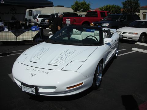 1998 Ford Crown Victoria - A white Pontiac Firebird convertible is parked at an outdoor event with other vehicles in the background.